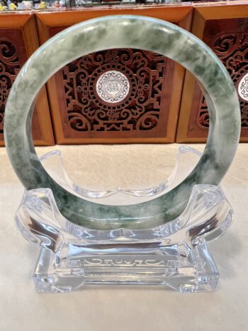 A green and white jade bangle sitting on top of a table.