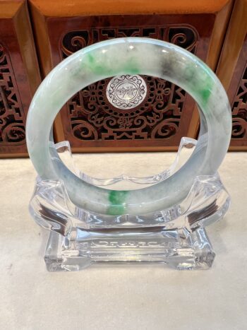 A green and white bangle sitting on top of a clear stand.