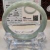 A green jade bracelet sitting on top of a clear glass display.