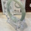 A green jade bangle is sitting in a clear plastic holder.