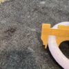 A toilet seat with a yellow ruler on it.