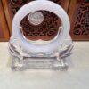 A clear glass sculpture with a white ring on top.