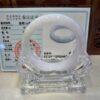 A white bracelet sitting on top of a clear glass holder.