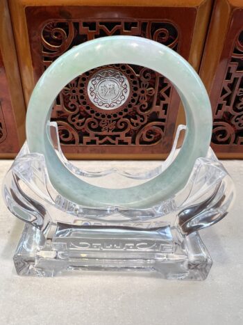 A large green jade ring sitting on top of a glass stand.