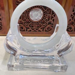 A clear glass sculpture with a white circle on top.