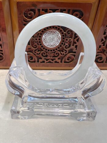 A clear glass sculpture with a white circle on top.