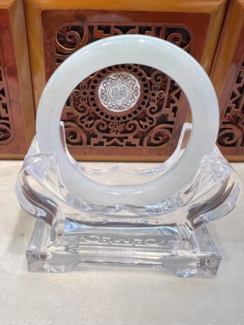 A clear glass sculpture with a white circle on top.