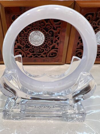 Crystal ring sculpture on ornate wooden background.
