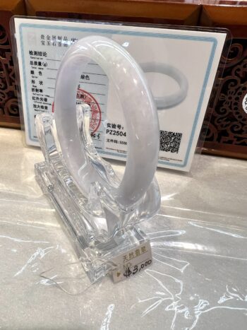 White jade bracelet on display with certificate.