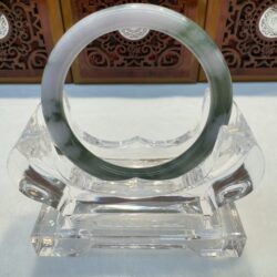 Green-streaked jade bangle on clear stand