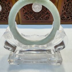Circular pale green jade bangle on clear stand