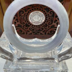 Circular jade ornament on ornate wooden stand.