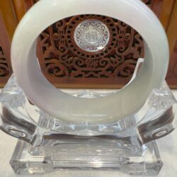 Green-gray jade circle resting in clear mount