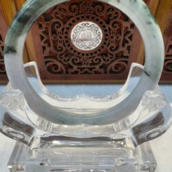 Jade circle on ornate wooden display stand.