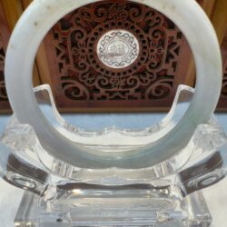 Circular jade bangle resting in clear holder