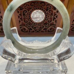 Pale jade wristlet centered against ornate wood