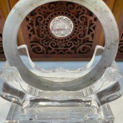 Jade bracelet on ornate wooden display stand.