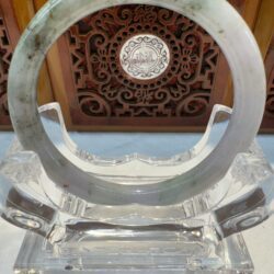 Round jade hoop resting before ornate wooden panel