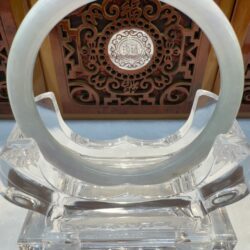 Circular jade display against wooden carving