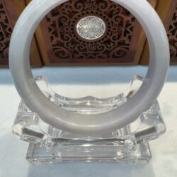 Light grey jade bangle against carved panel