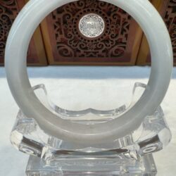 Jade bangle framed by carved wooden panel