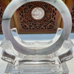 Jade bangle centered before carved wooden panel
