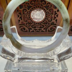 Jade bracelet on a decorative wooden stand.
