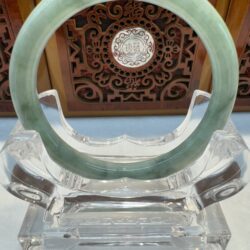 Green jade bangle on clear display stand.