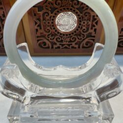 Jade bangle displayed on a clear stand.