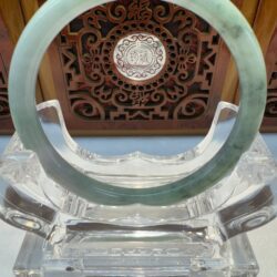 Pale green jade bangle on clear acrylic stand