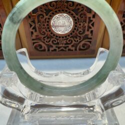 Green jade bracelet on ornate display stand.