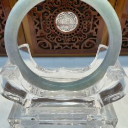 Jade ring displayed on decorative wooden stand.
