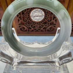 Pale green jade circle on crystal stand