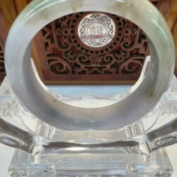 Decorative jade bangle on carved stand.