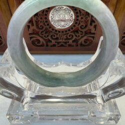 Green jade bracelet on ornate display stand.