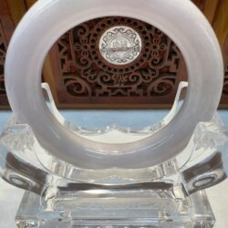 Translucent jade ring on ornate wooden stand.
