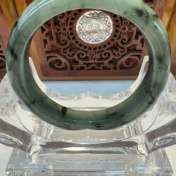 Green jade bangle on ornate stand display.