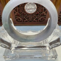 Circular jade bracelet on ornate display stand.
