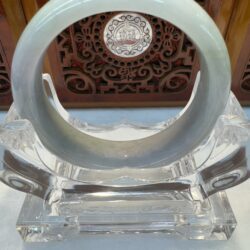 Translucent jade bracelet resting on clear mount