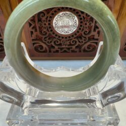 Green jade bangle on decorative display stand.