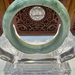 Translucent green jade bracelet on acrylic holder