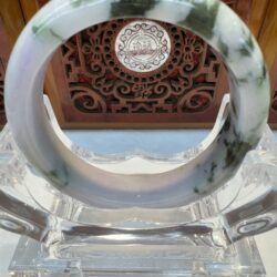 Jade bracelet on intricate wooden display stand.