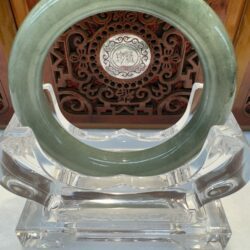 Deep green polished jade bangle on clear stand