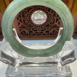 Green jade ring on clear display stand.