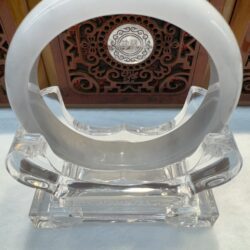 Crystal ring sculpture on ornate wooden stand.