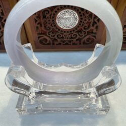 Transparent circular sculpture on decorative stand.