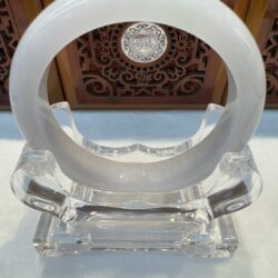 Circular white jade sculpture on display stand.