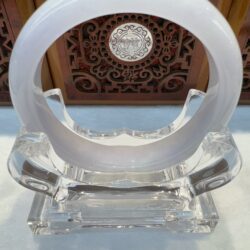 White circular sculpture on a clear stand.
