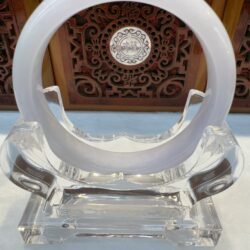 Transparent circular sculpture on ornate background.