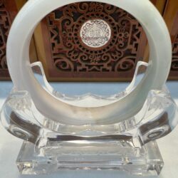 Crystal jade bangle on decorative wooden stand.